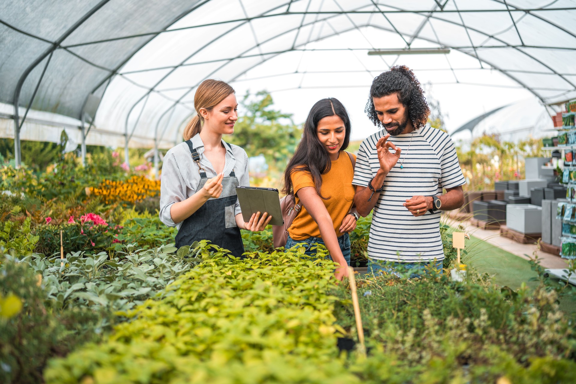 Caucasian Female Gardener Assisting Diverse Couple in Garden Center